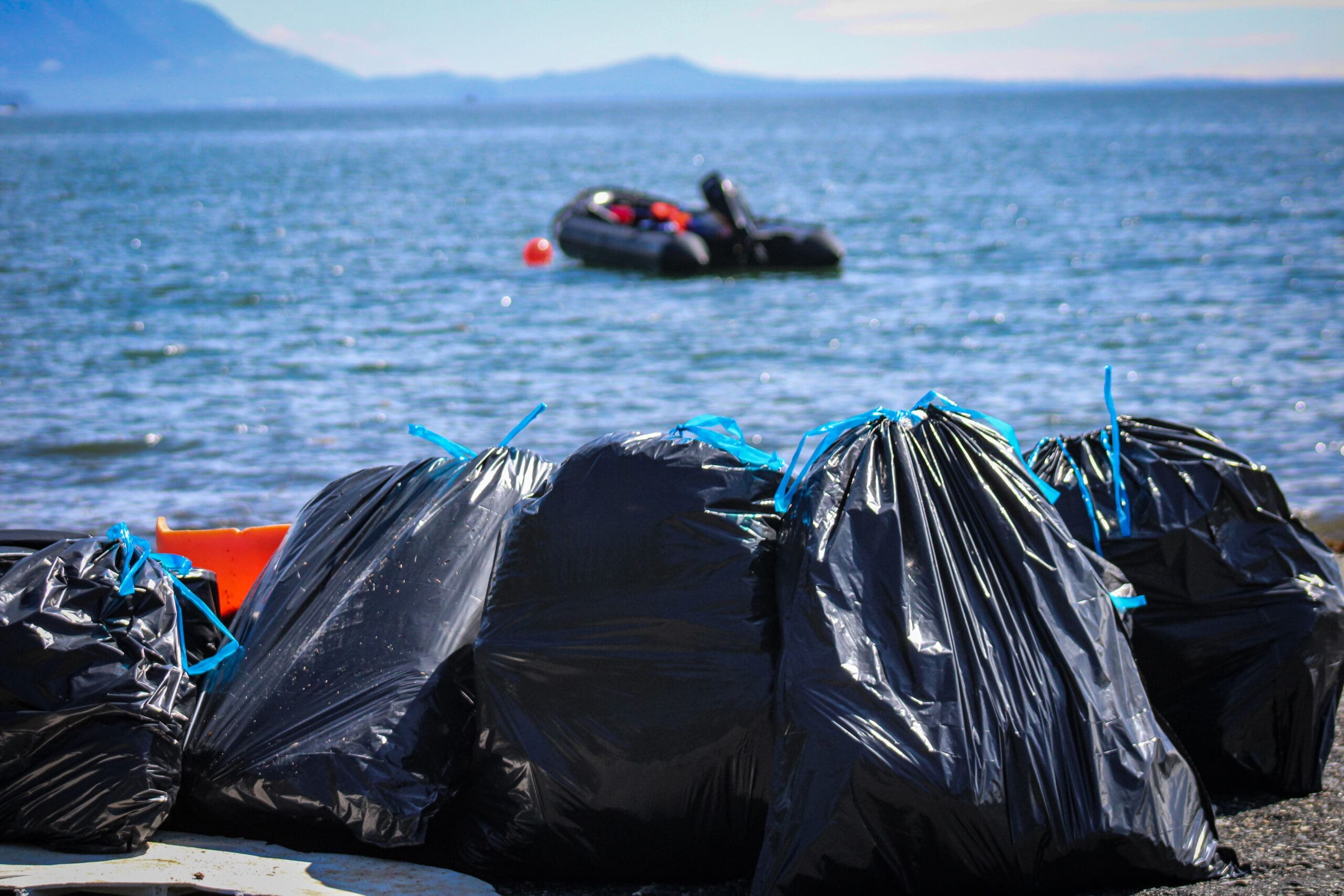 Trash bags full of marine debris with a Zodiac in the background