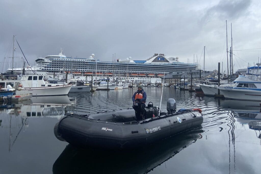 Zodiac boat docking in Thomas Basin Boat Harbor with cruise ship in background