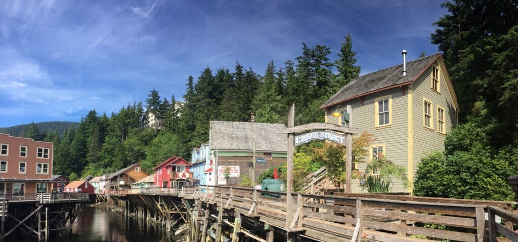 Colorful historic buildings on a boardwalk above water behind a "Creek Street" sign