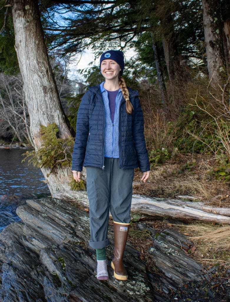 A woman in outdoor clothing shows how to dress in layers to stay warm on the water
