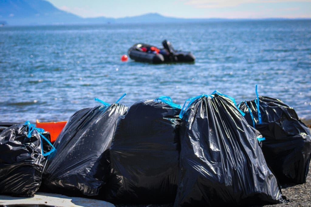 Beach Cleanup Trash bags on a beach in front of a Zodiac boat